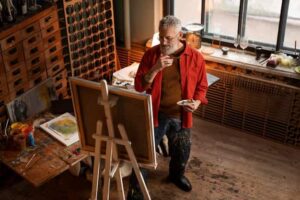 L'uomo con la camicia rossa sta dipingendo un quadro