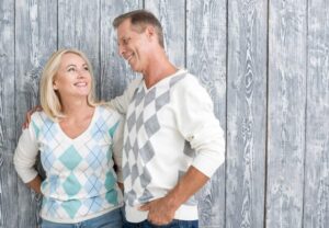 l'uomo e la donna si guardano e si abbracciano, in piedi vicino al muro grigio di legno