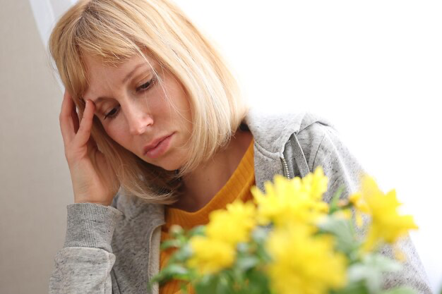 La ragazza con il mazzo di fiori si tiene la testa